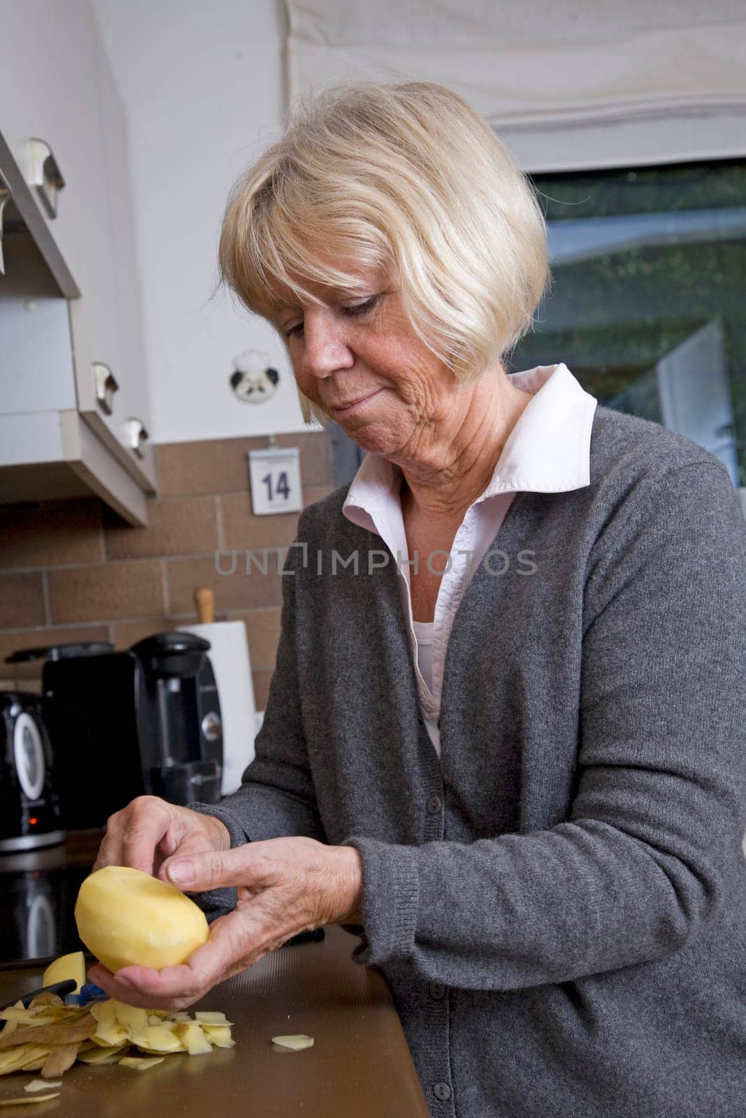 Senior woman peels potatoes