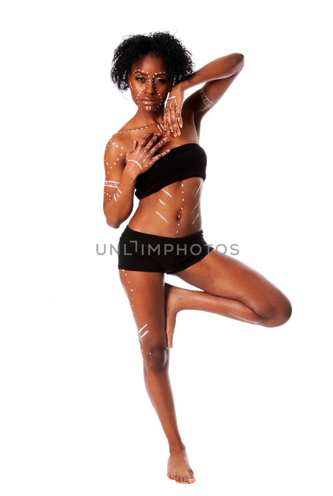 Beautiful African indigenous tribal fashion female with white dots and stripes standing balancing on one leg, isolated.