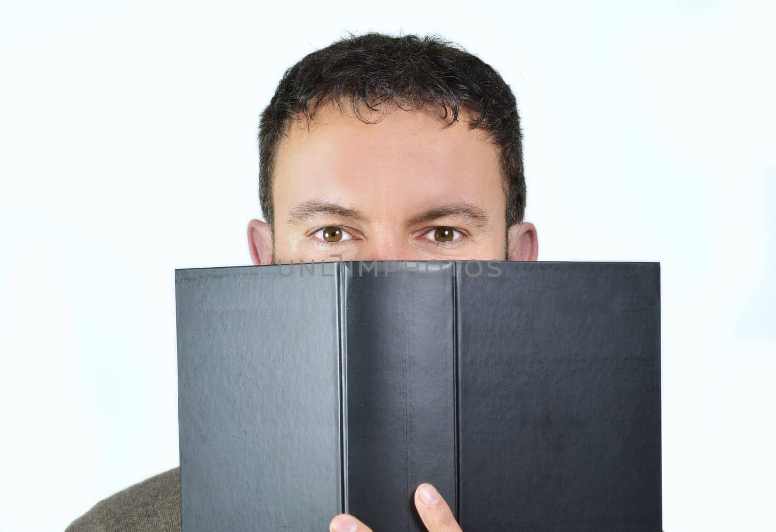 Handsome young man behind a big book, isolated on white