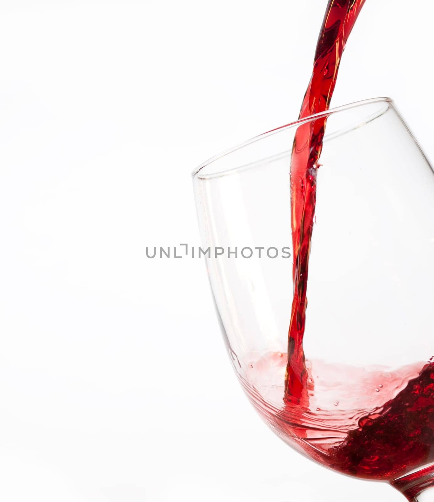 Red wine pouring into glass, isolated on white background