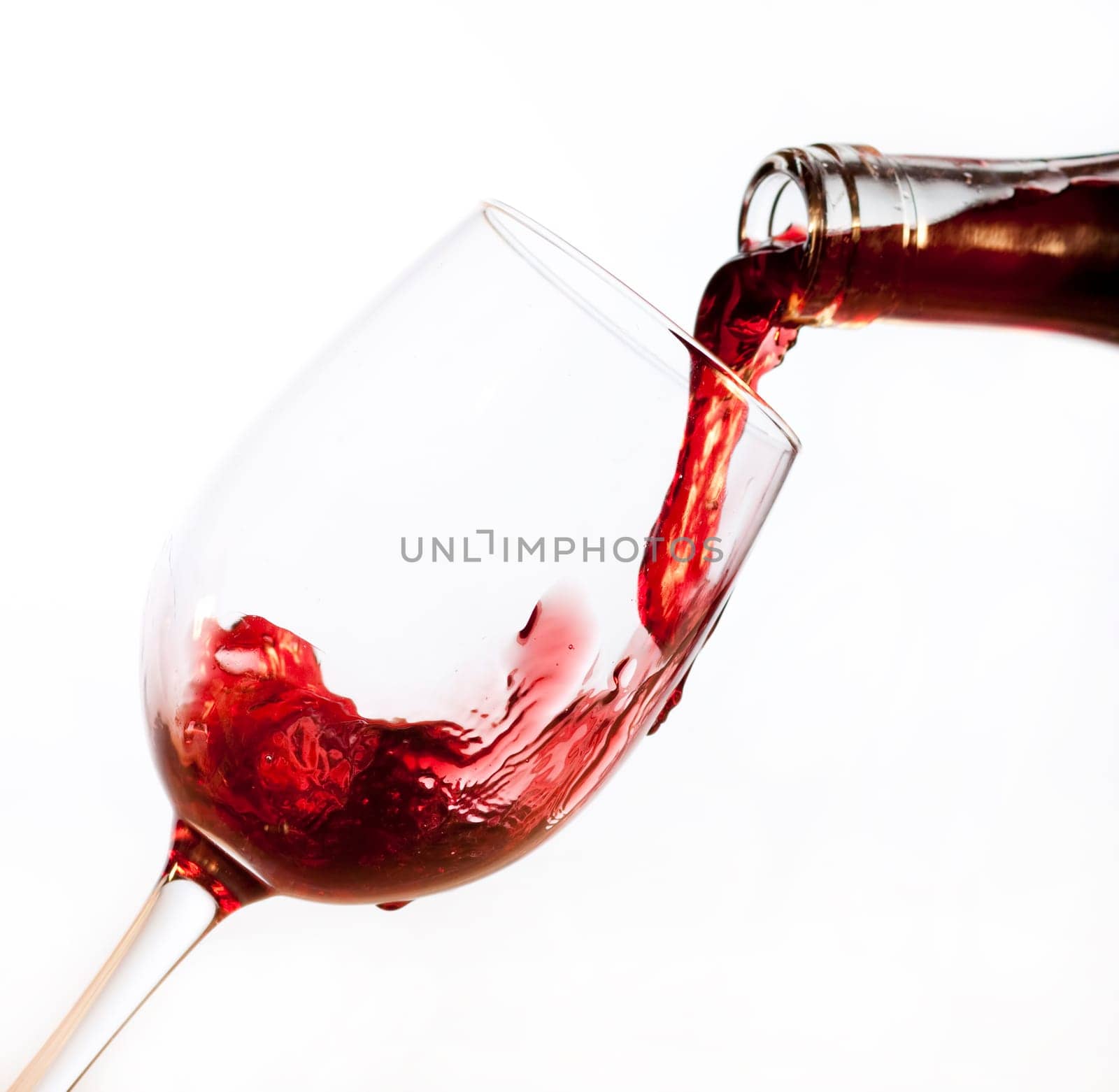 Red wine pouring into glass, isolated on white background