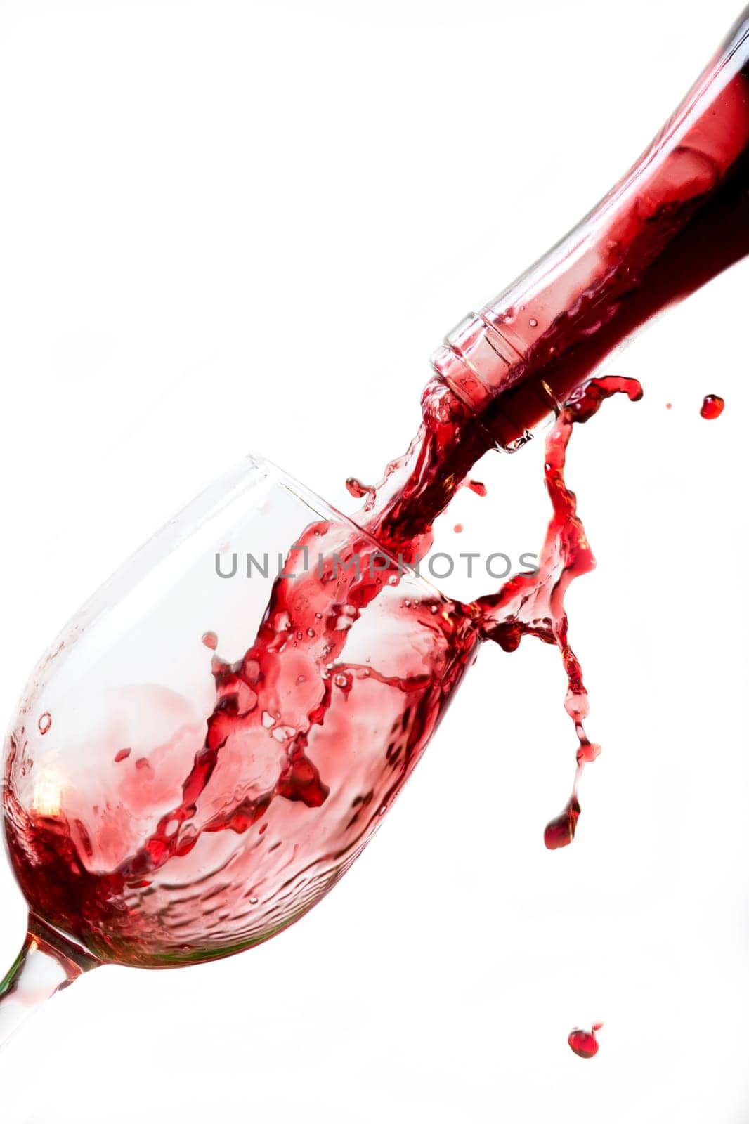 Red wine pouring into glass, isolated on white background