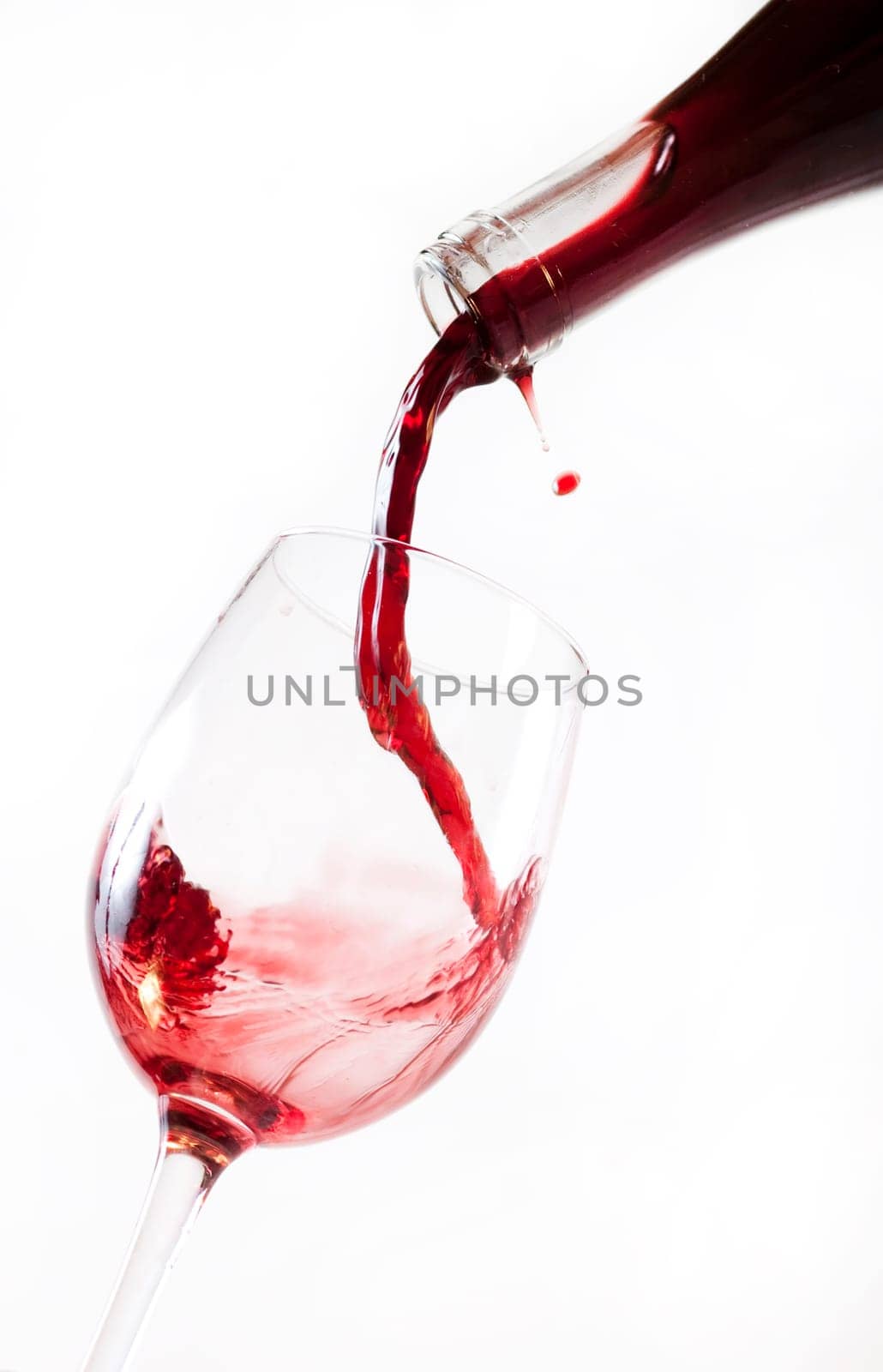 Red wine pouring into glass, isolated on white background