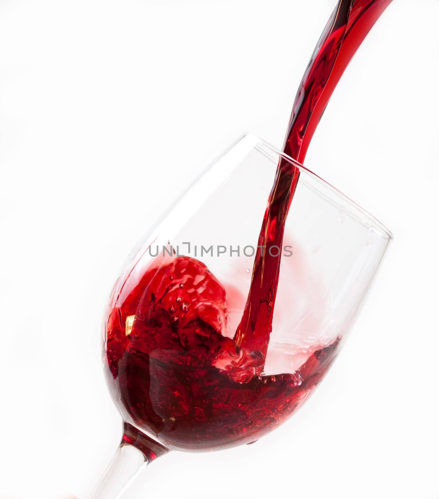 Red wine pouring into glass, isolated on white background