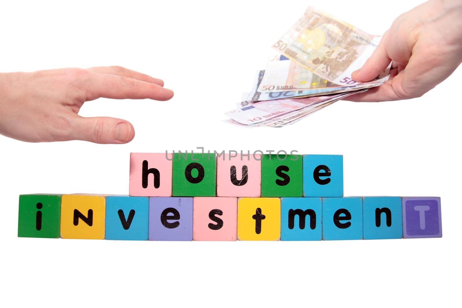 toy letters that spell house investment with cash in hands against a white background with clipping path