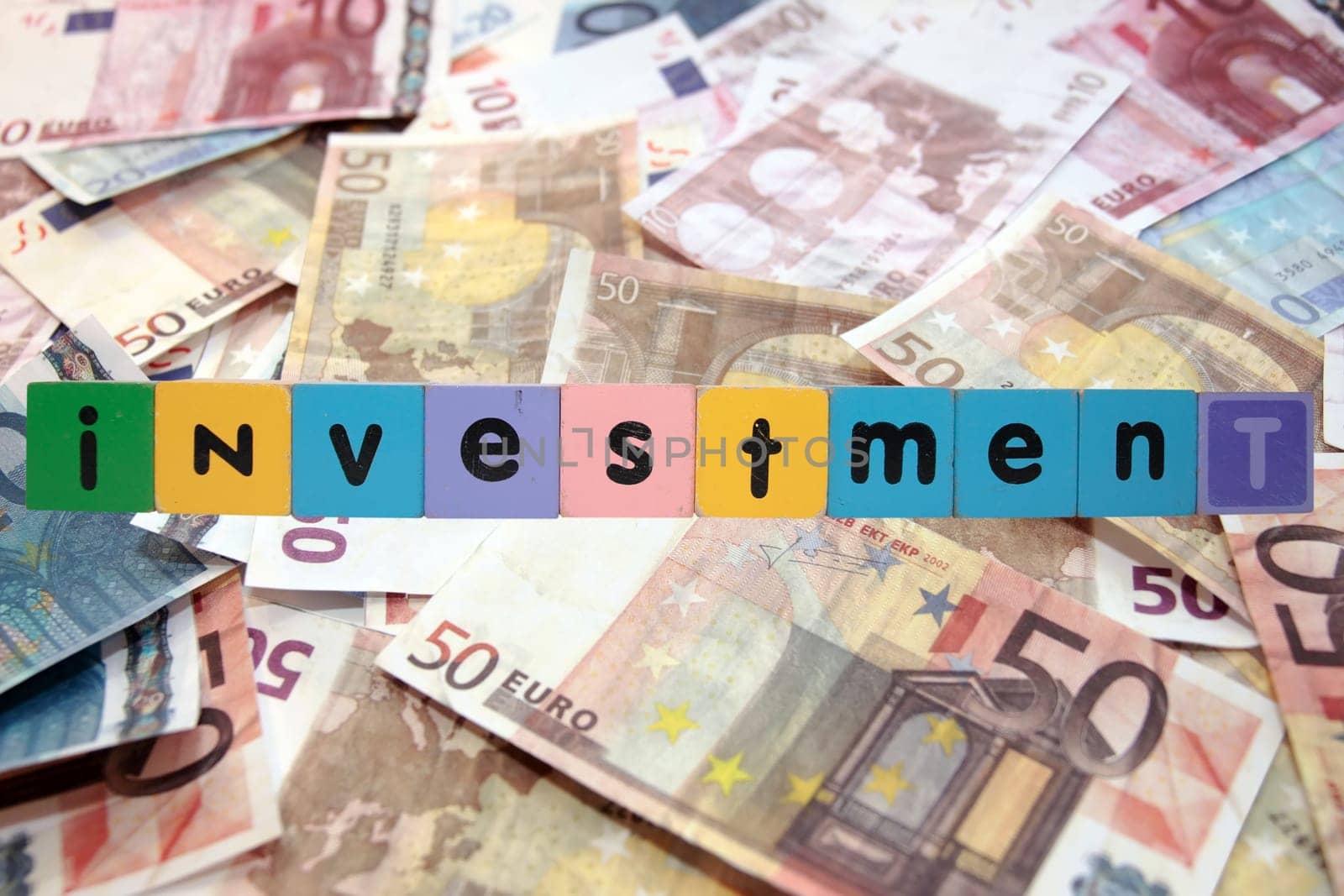 toy letters that spell house investment against a money background with clipping path