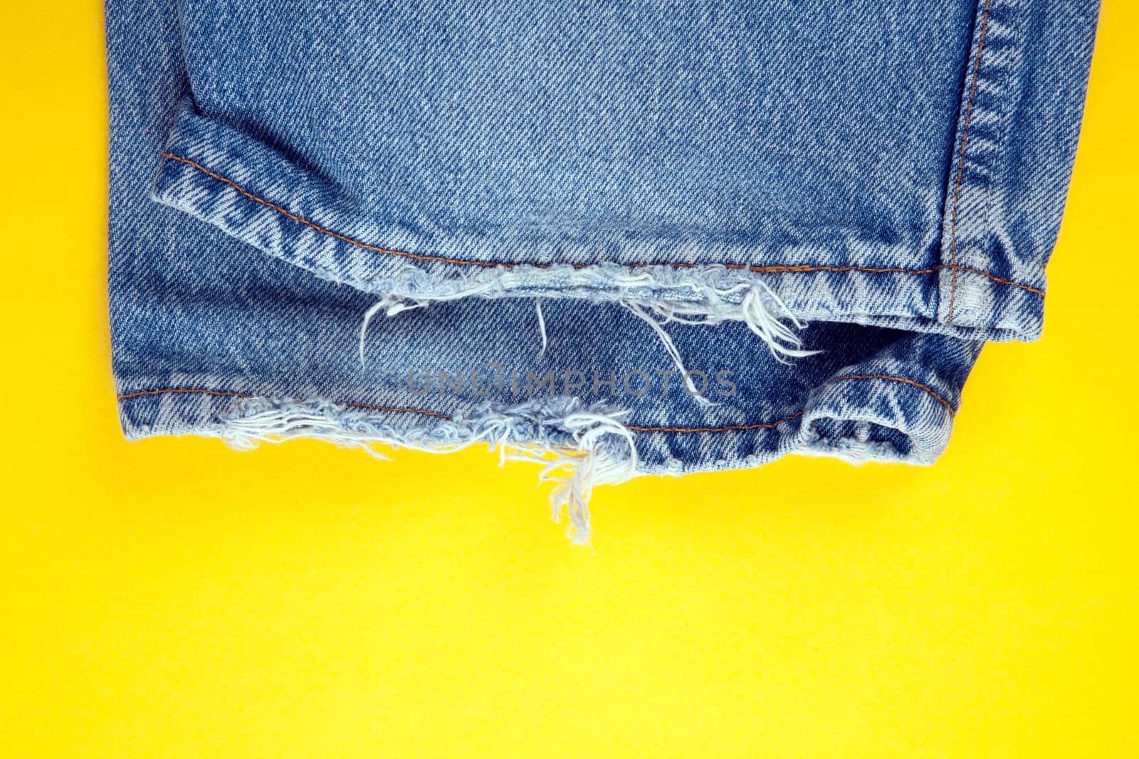 Frayed denim jeans  with yellow background