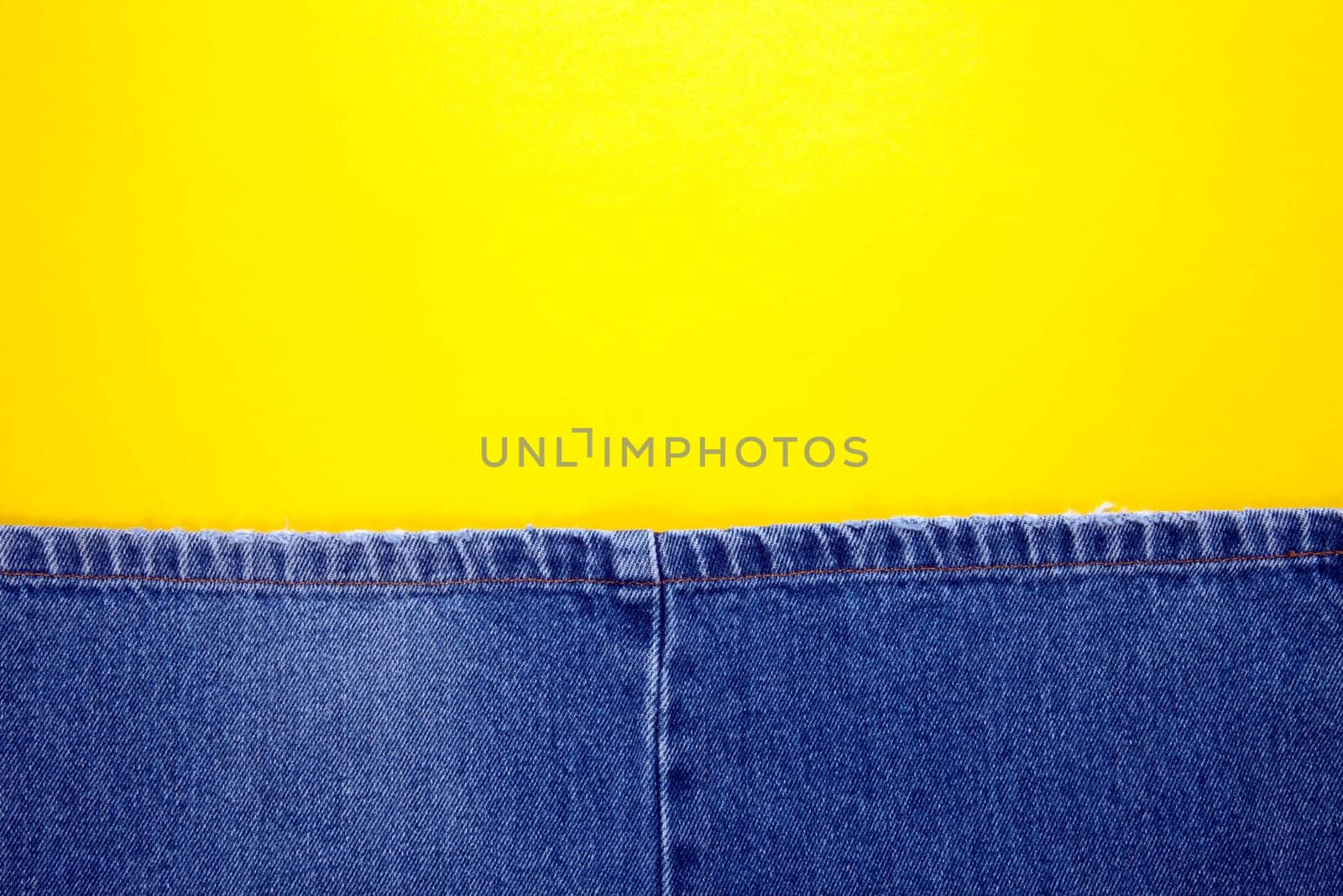 Blue jeans with yellow stitches and yellow background