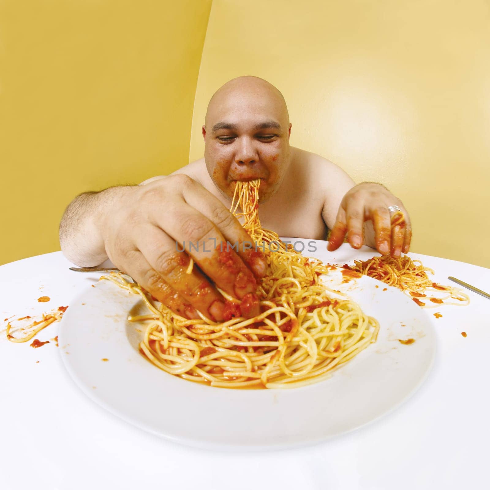 An overweight man enjoying a plate of spaghetti.  Shot with fish-eye lens.  Focus is on the face.