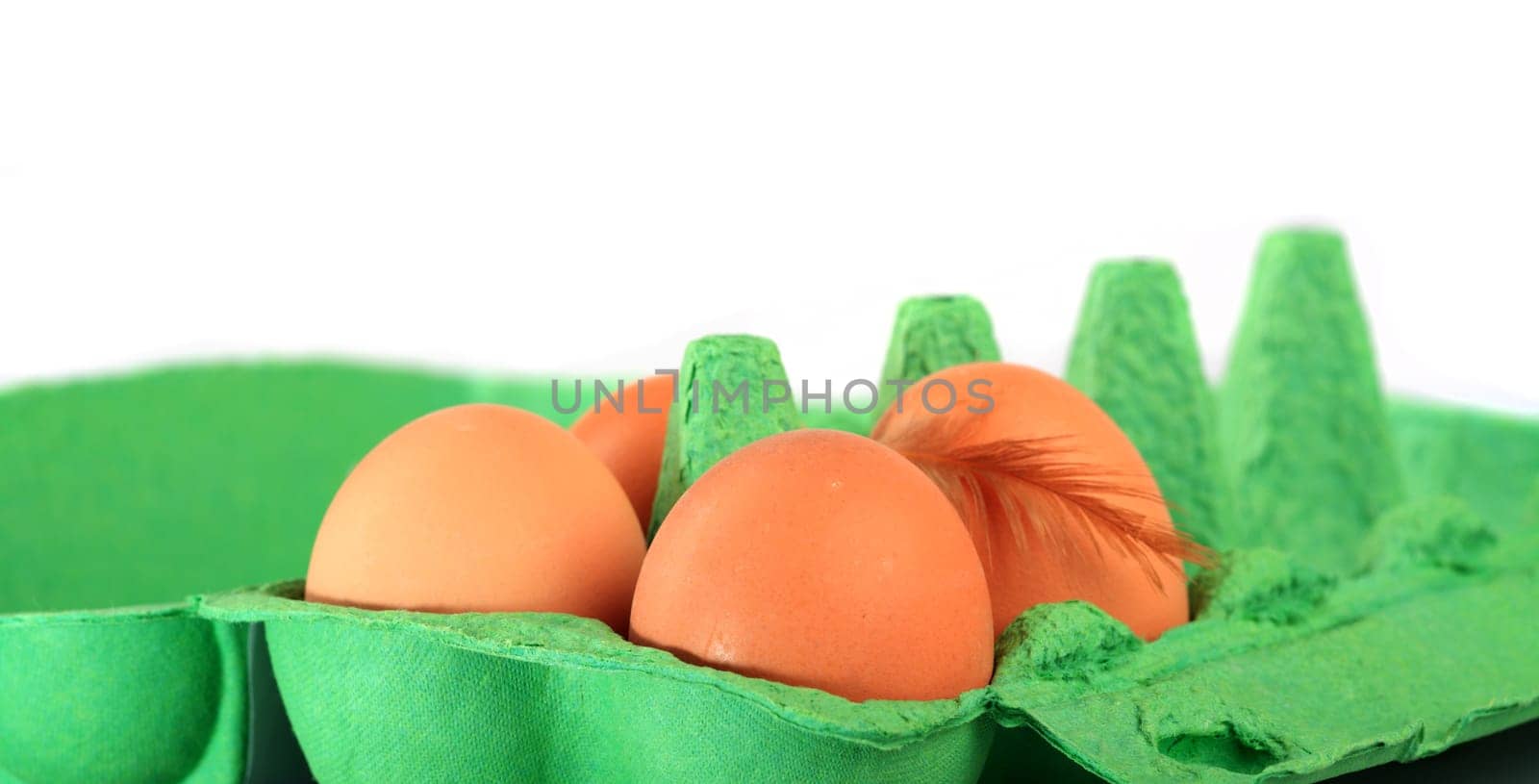 Brown chicken eggs in a cardboard box with down feather