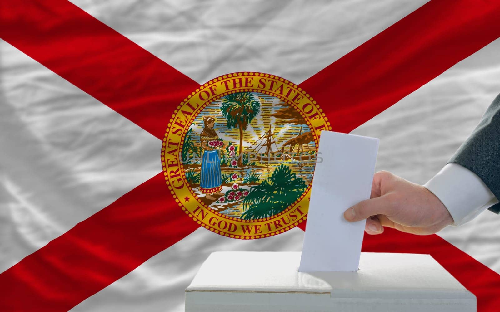 man putting ballot in a box during elections  in front of flag american state of florida