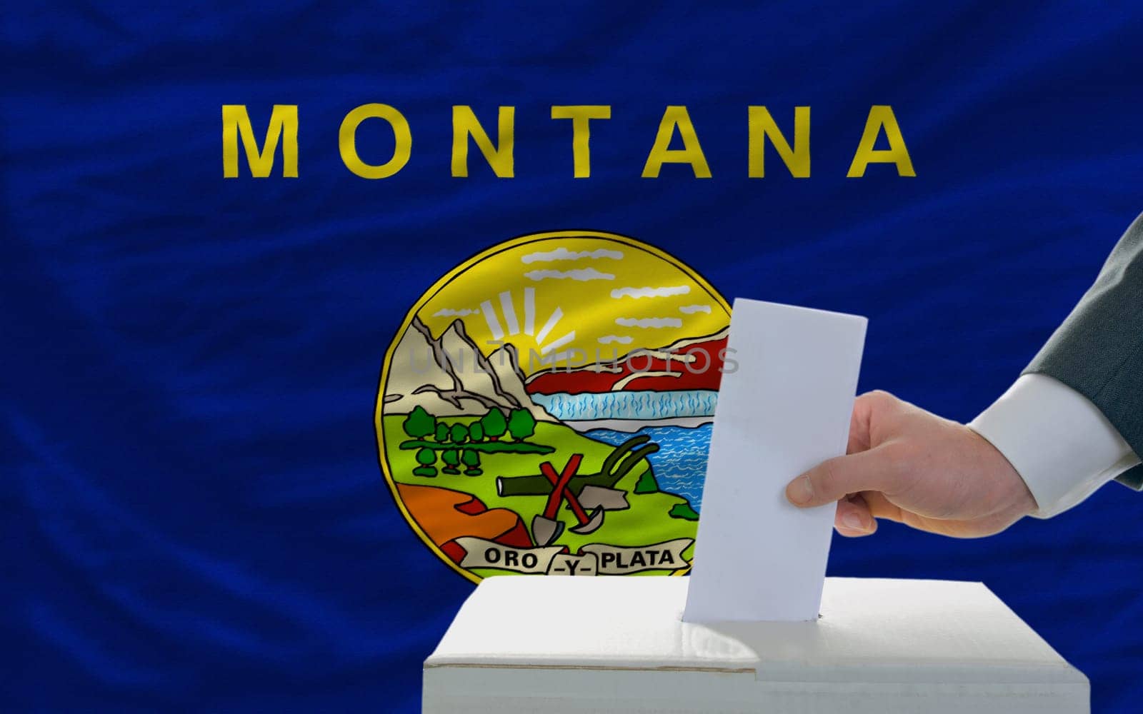 man putting ballot in a box during elections  in front of flag american state of montana