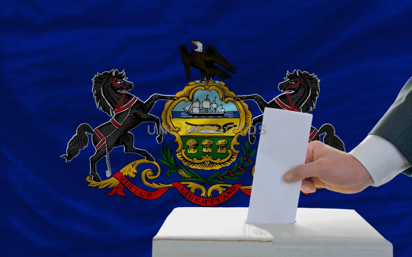 man putting ballot in a box during elections  in front of flag american state of pennsylvania