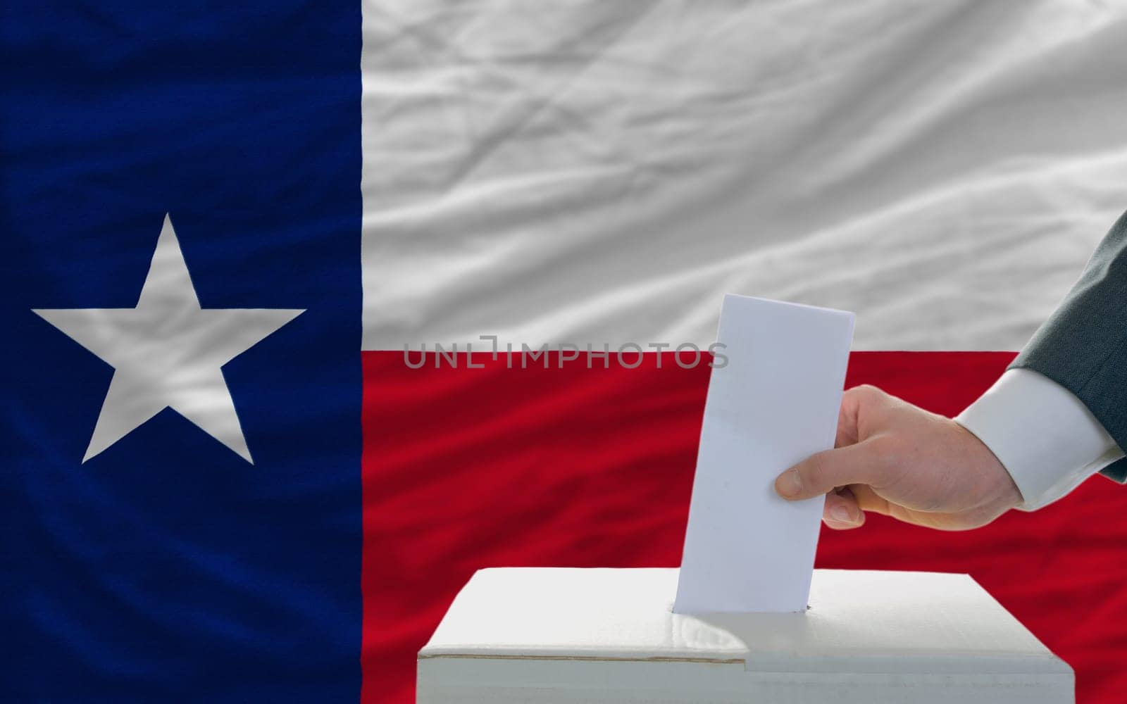 man putting ballot in a box during elections  in front of flag american state of texas