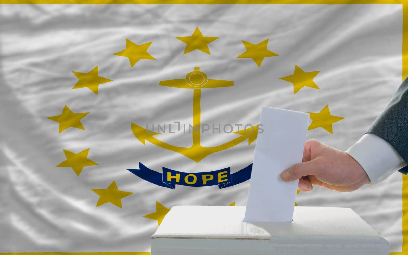man putting ballot in a box during elections  in front of flag american state of rhode island