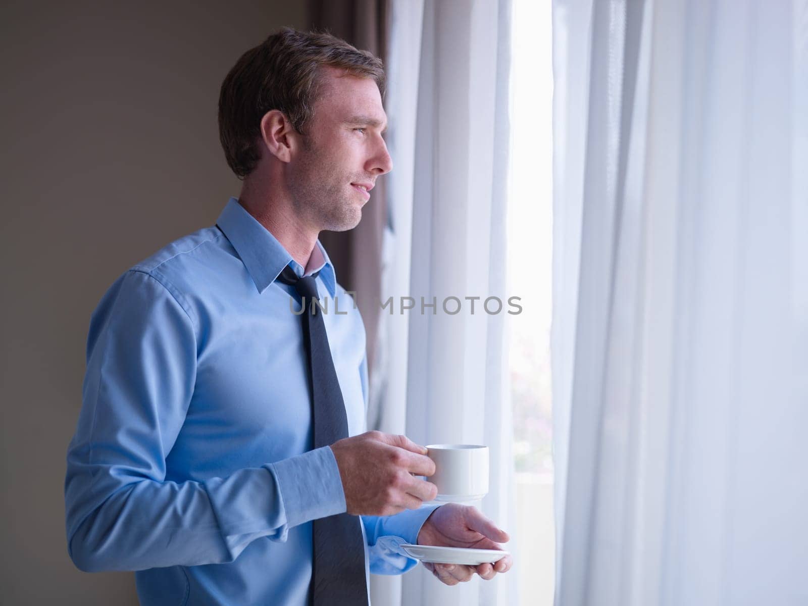 Mid adult business man relaxing and drinking a cup of tea, looking out of window. Side view, copy space