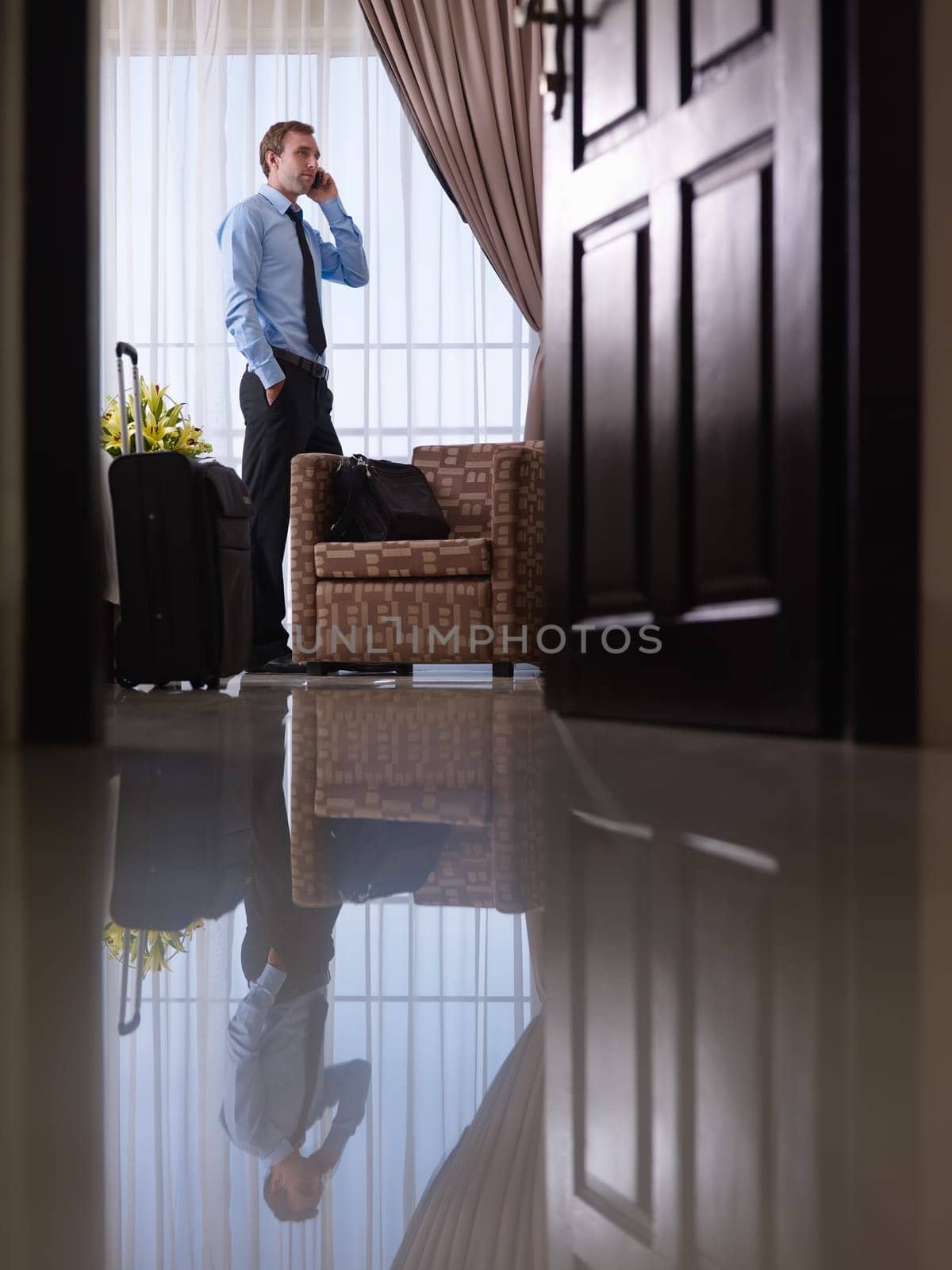 Caucasian mid adult businessman talking with mobile telephone in hotel room during business trip