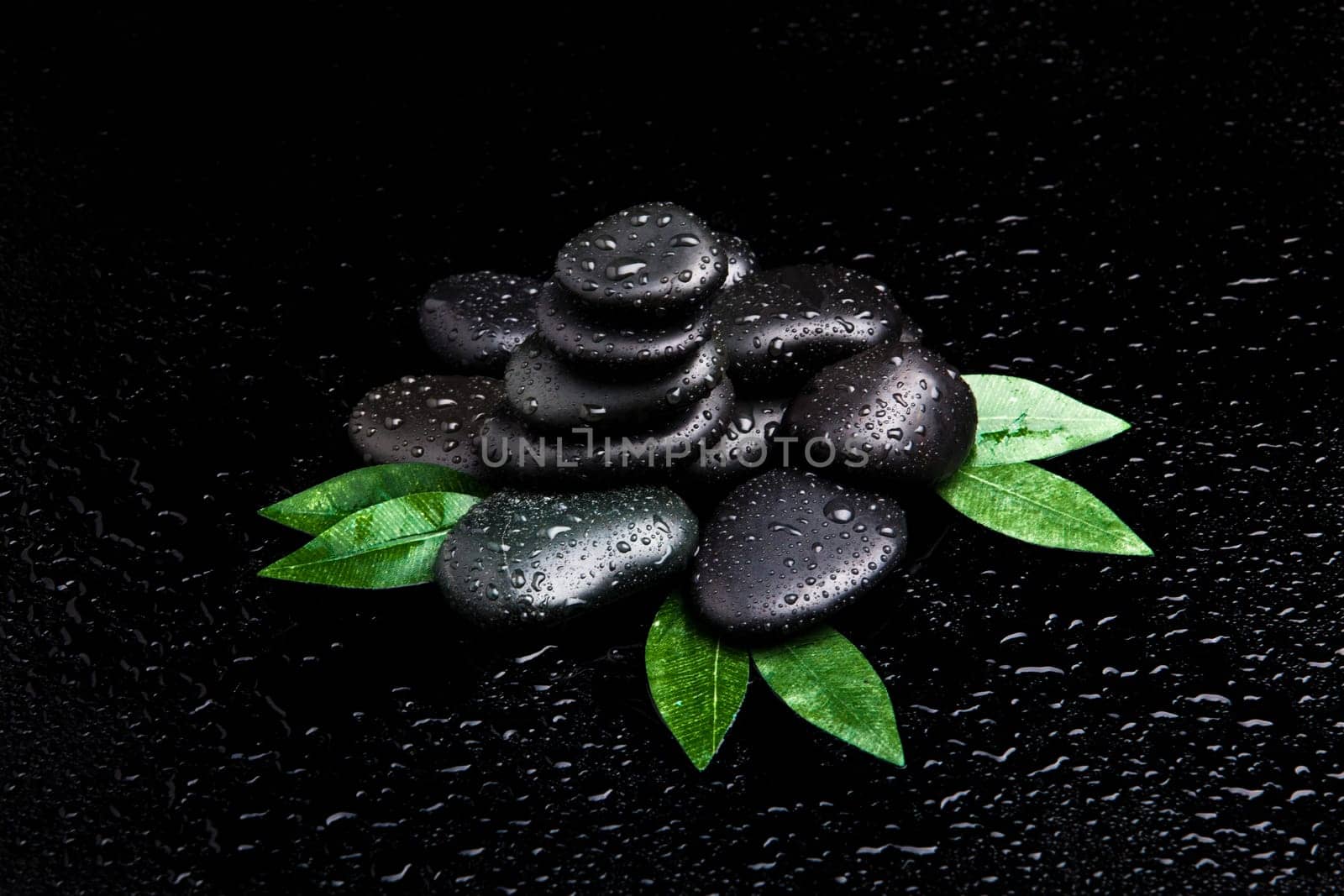 zen stones and leaves with water drops. leaf and basalt stones.