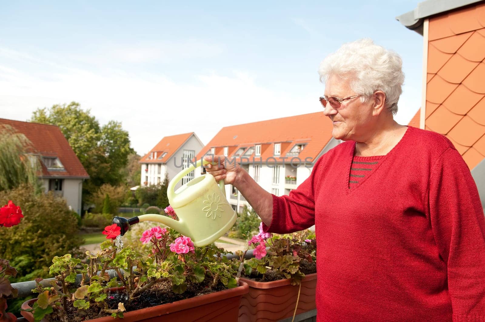 Senior woman watering flowers on the balcony