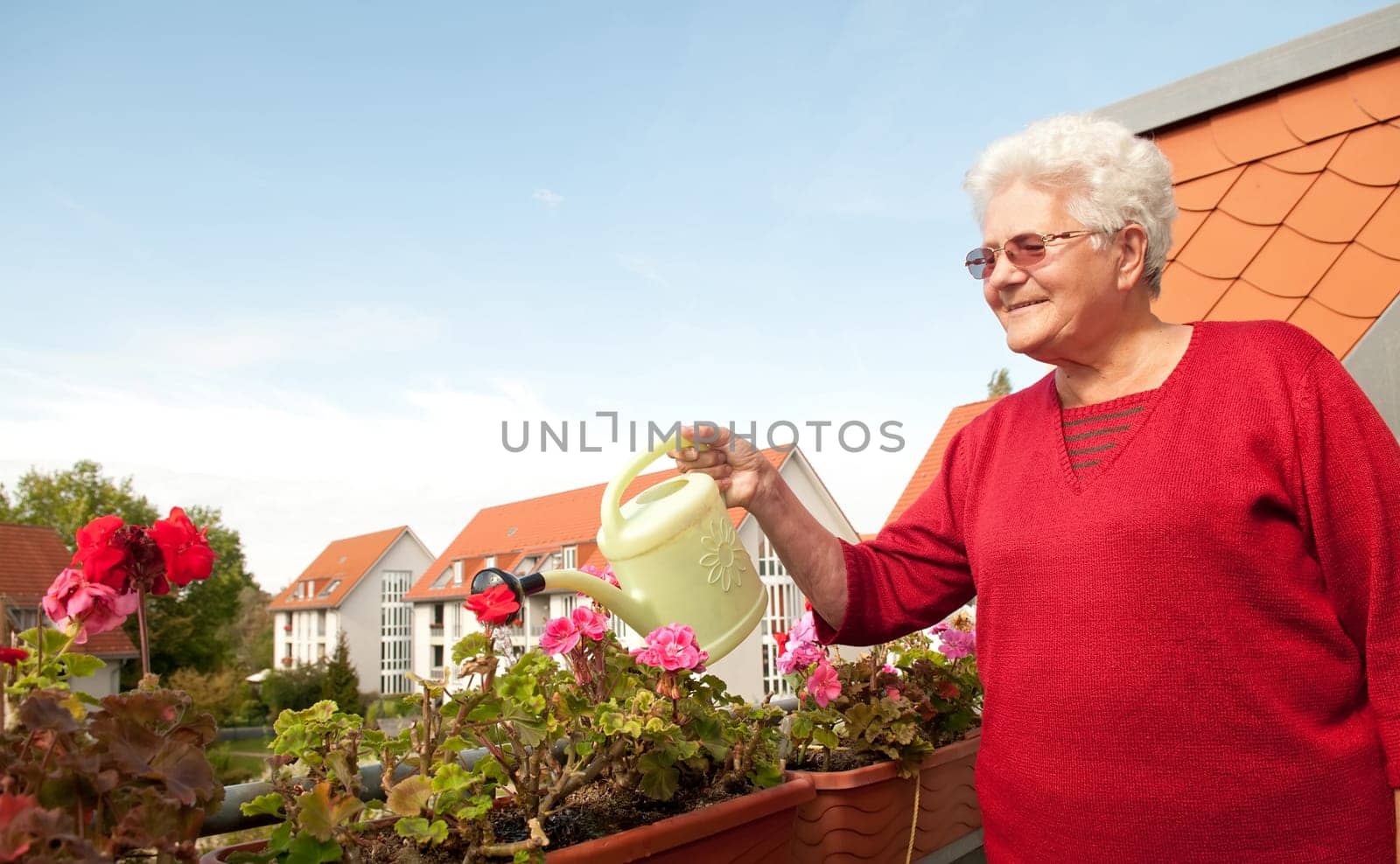 Senior woman watering flowers on the balcony