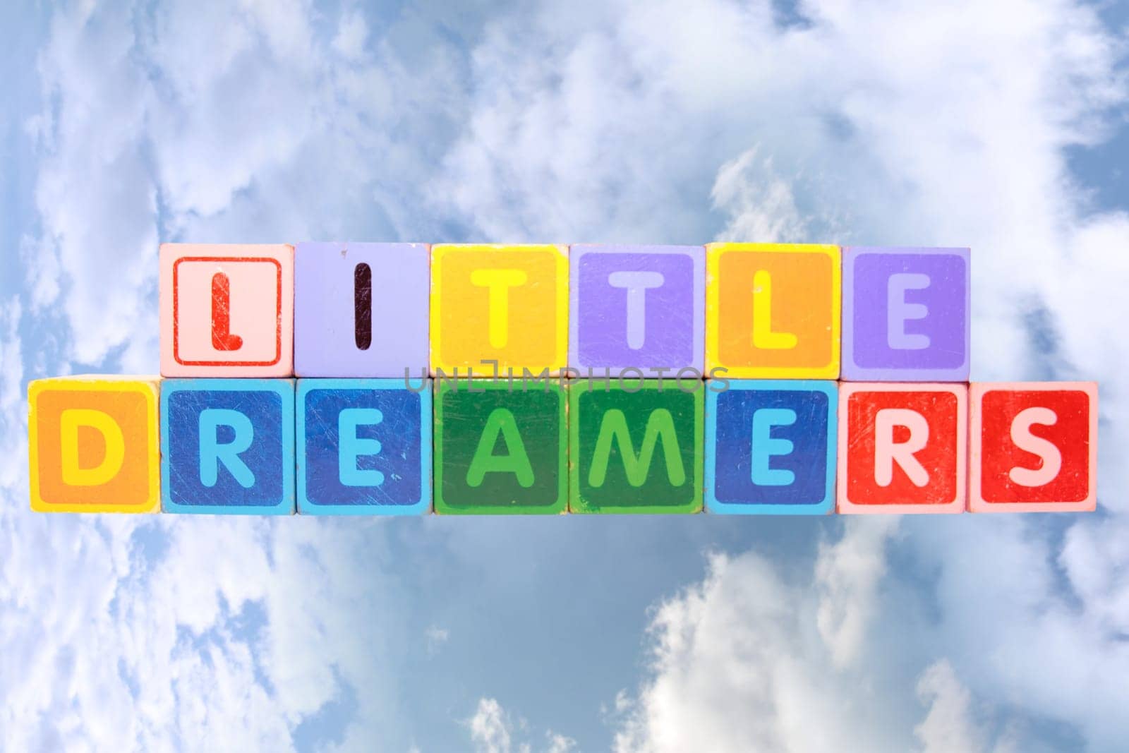toy letters that spell little dreamers against a cloudy background with clipping path