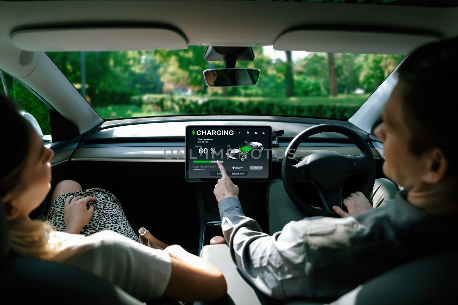 Electric car driver checks battery charging status, range and charging limit on app screen in the car. Smart technology device show EV car recharging data of electric storage in car battery innards.