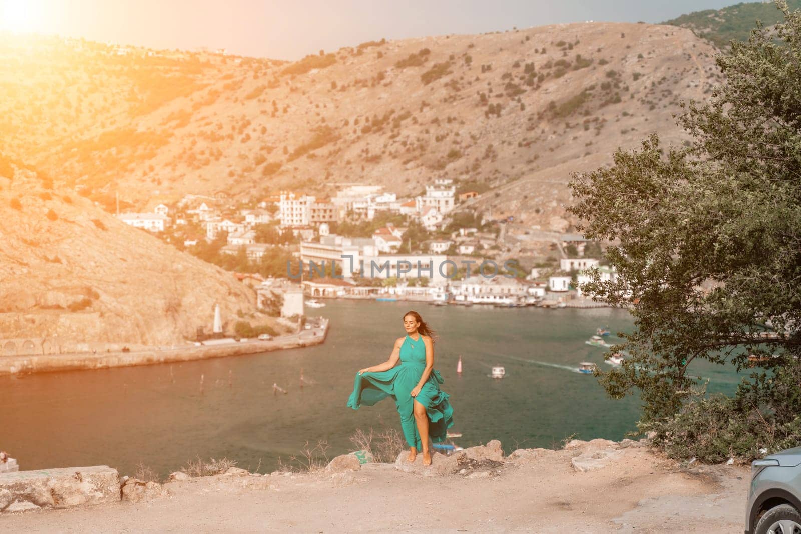 Woman sea trevel green dress. Side view a happy woman with long hair in a long mint dress posing on a beach with calm sea bokeh lights on sunny day. Girl on the nature on blue sky background. by Matiunina