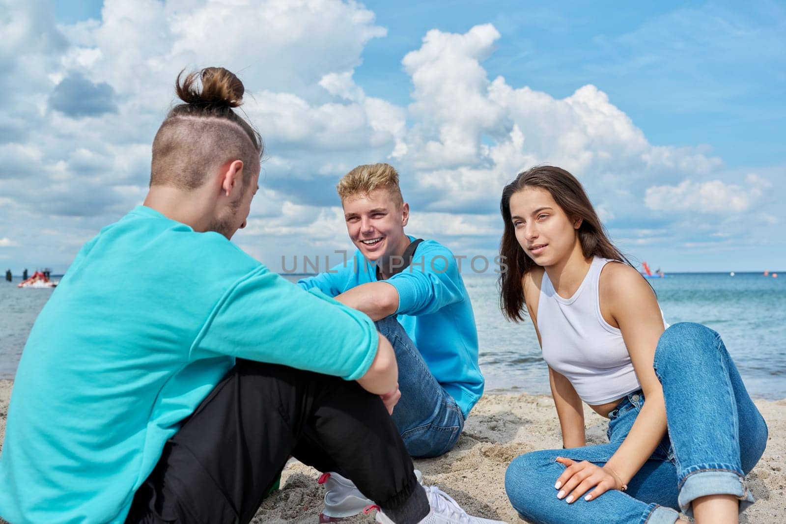 Friends teenagers talking sitting on sand on beach by VH-studio