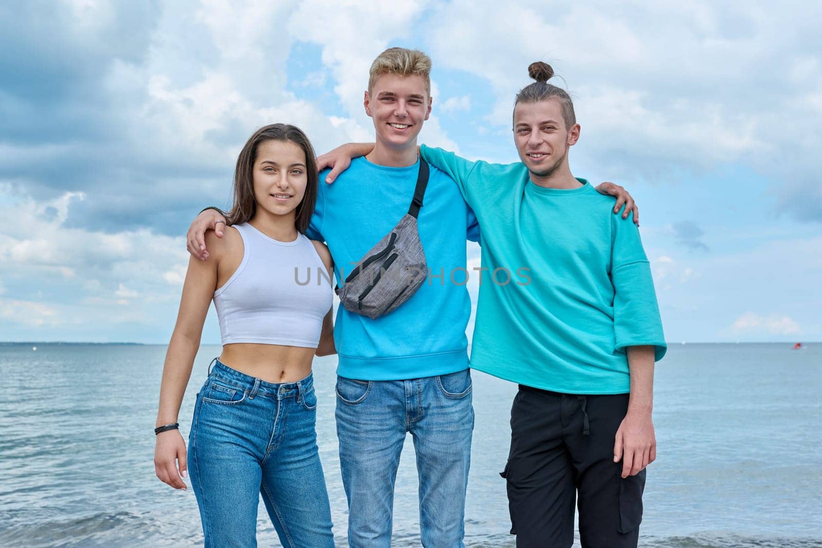 Portrait of cheerful teenage friends hugging on beach by VH-studio