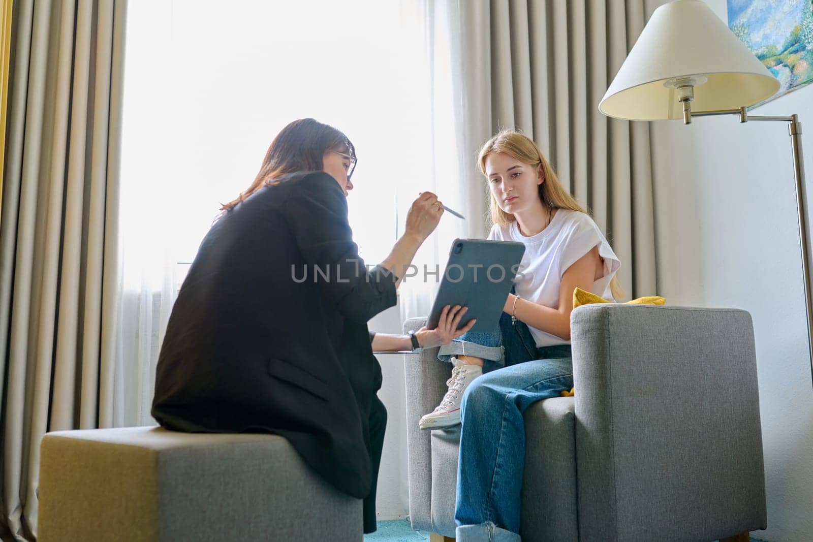 Young female at therapy meeting with psychotherapist. Session of teenage student girl, specialist psychologist with digital tablet talking to patient. Psychology, psychotherapy, treatment, youth mental health