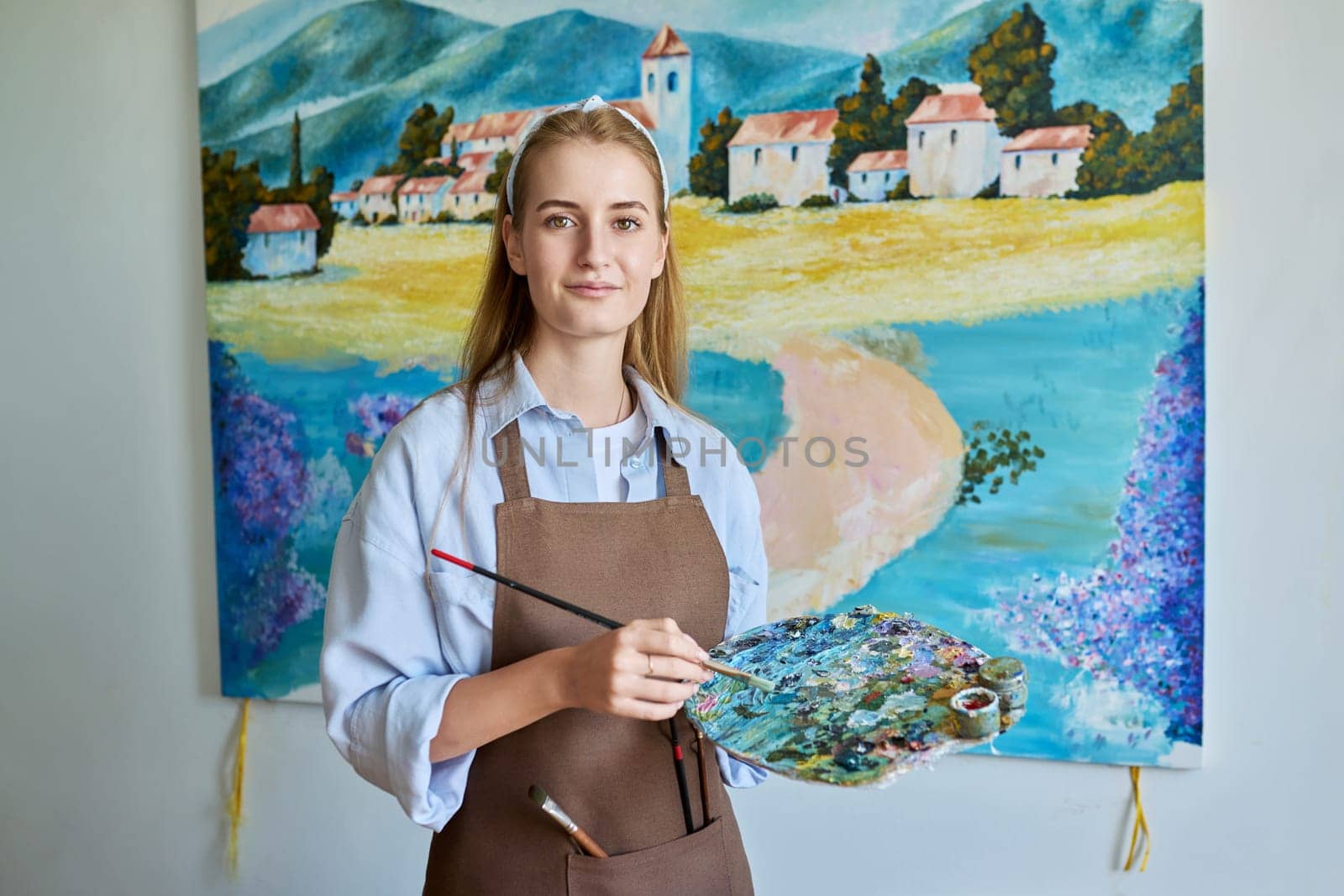 Portrait of young woman artist painting picture on canvas by VH-studio
