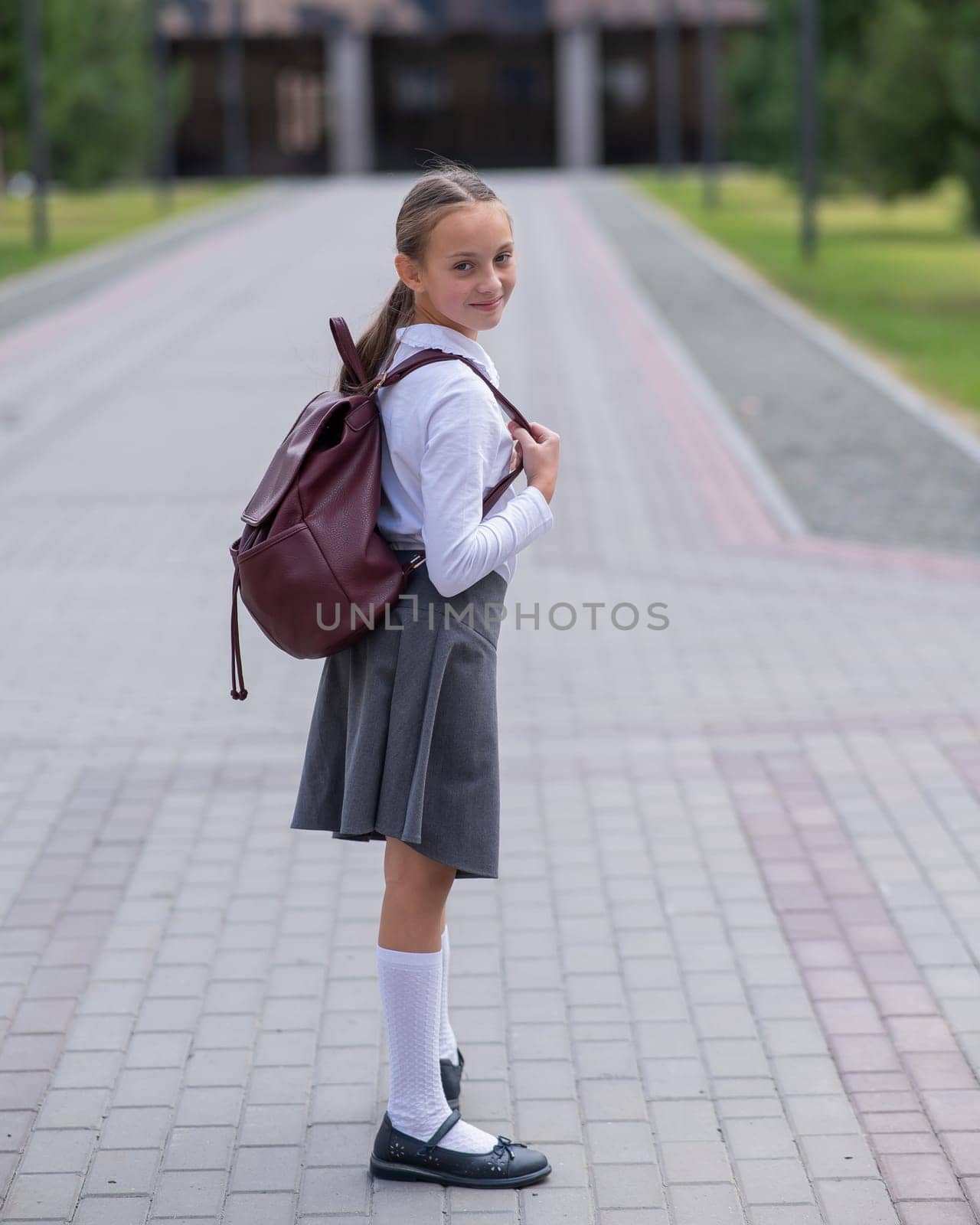 Portrait of caucasian schoolgirl in uniform and with backpack outdoors