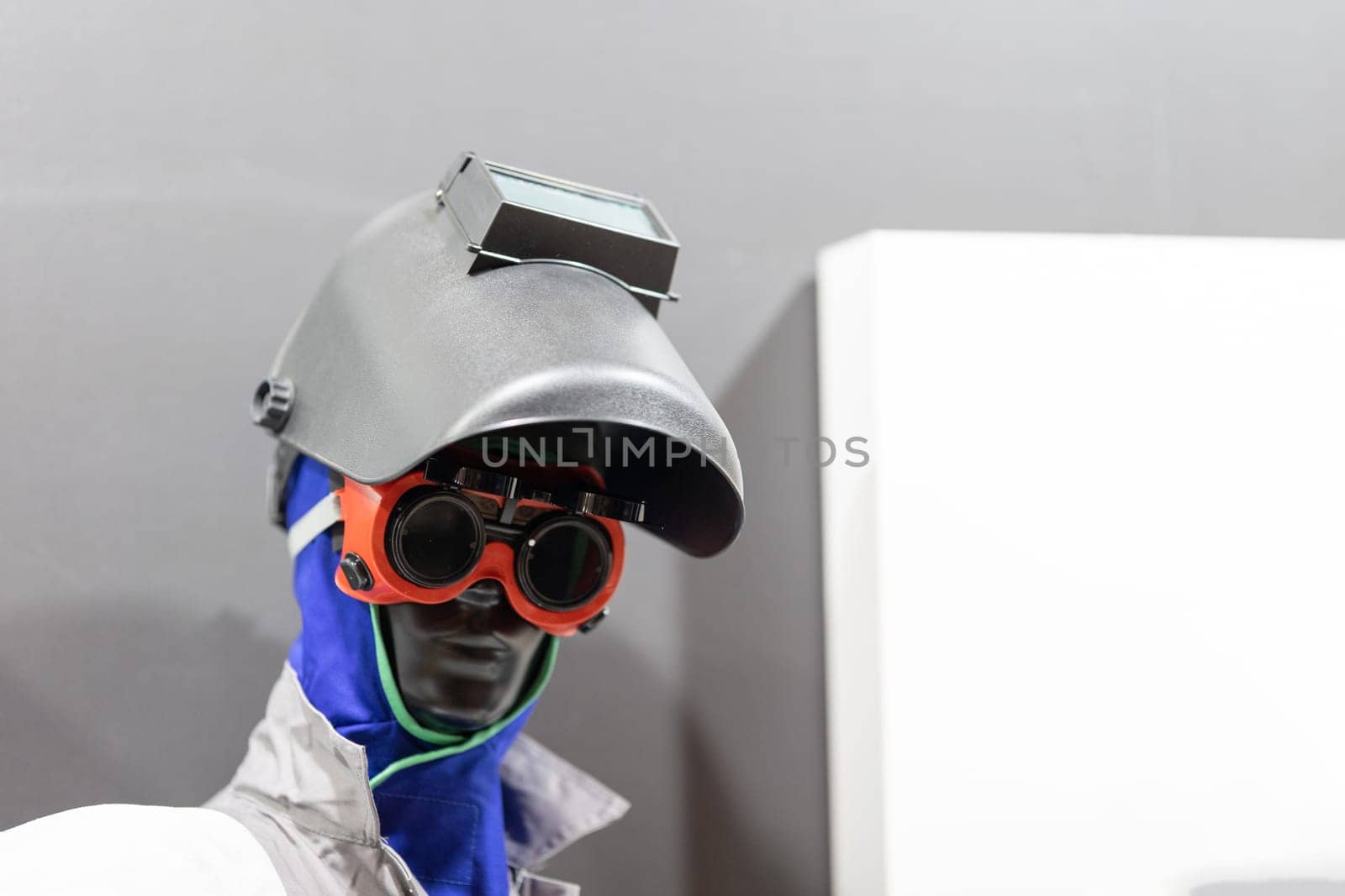 A mannequin wearing safety sunglasses holding and showcasing a tool.