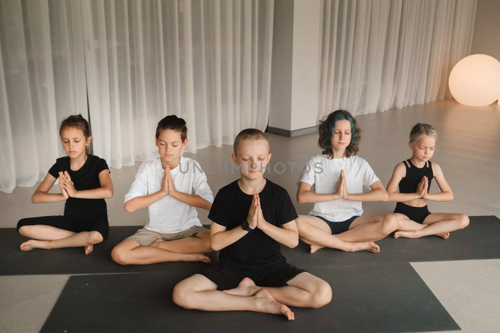 Children sit on mats in the lotus position in Yoga classes. Children's yoga.