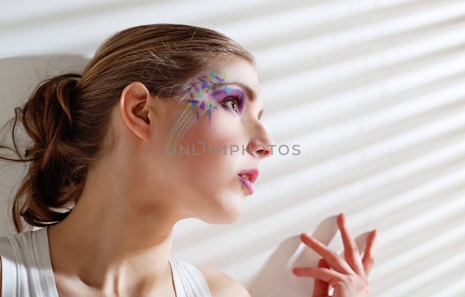 Pretty young woman lean lit by bright sunlight coming through the blinds