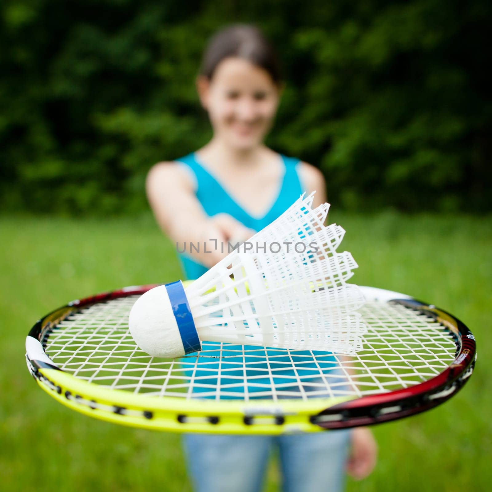 Pretty, young woman playing badminton in a city park on a lovely summer day (shallow DOF)