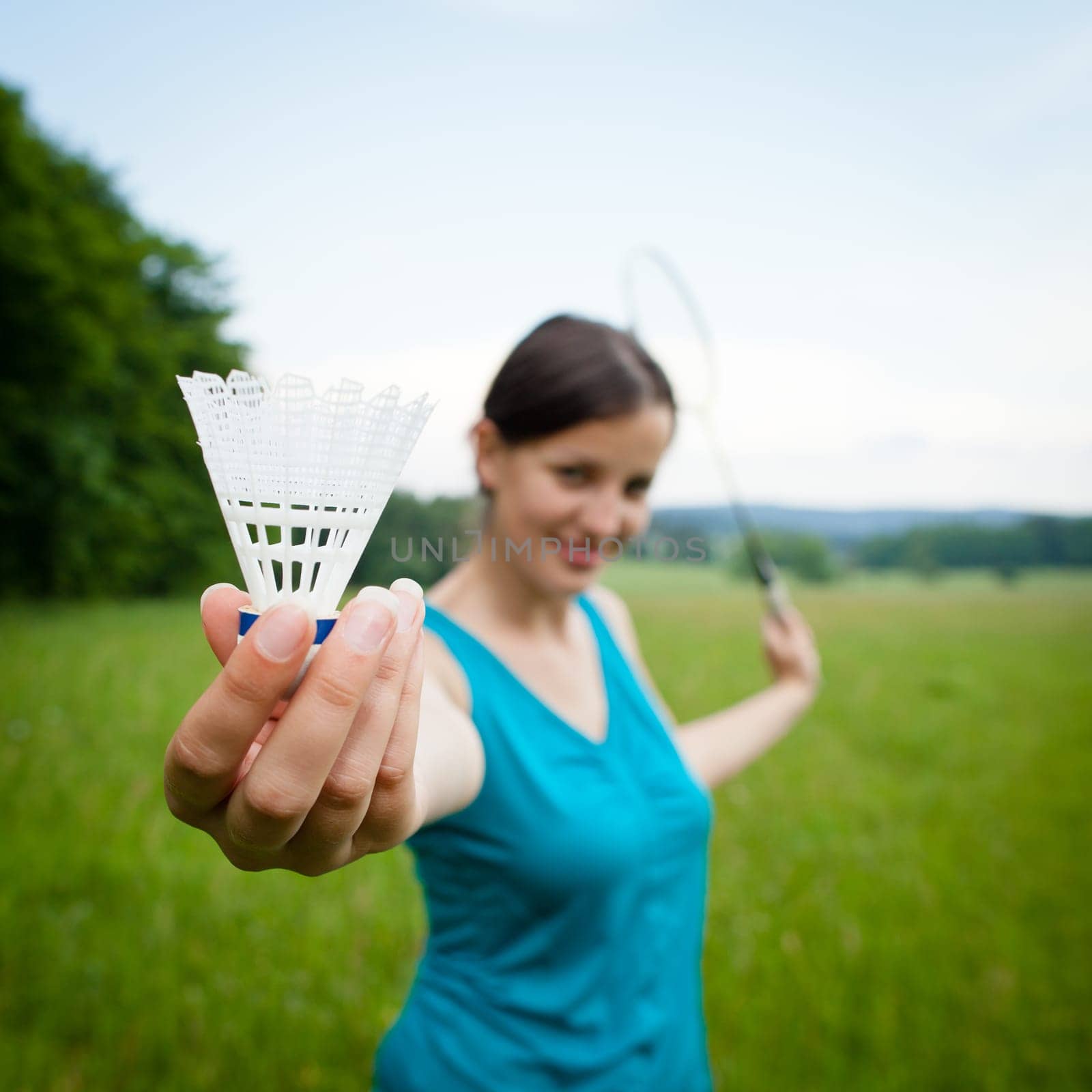 Pretty, young woman playing badminton in a city park on a lovely summer day (shallow DOF)