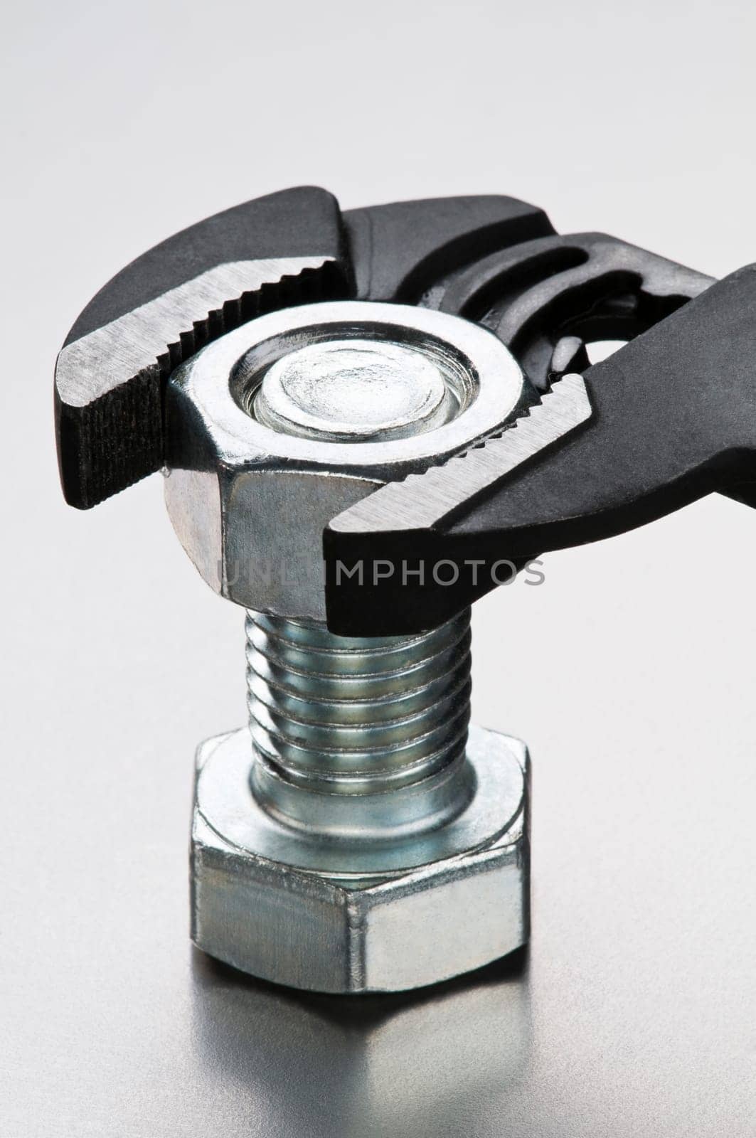 Pliers and silver bolt on metallic background close up