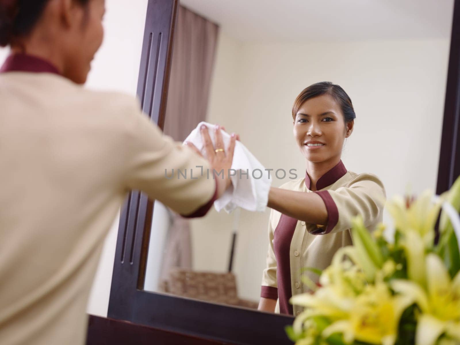 Portrait of happy Asian housekeeper at work in luxury hotel room and smiling at camera