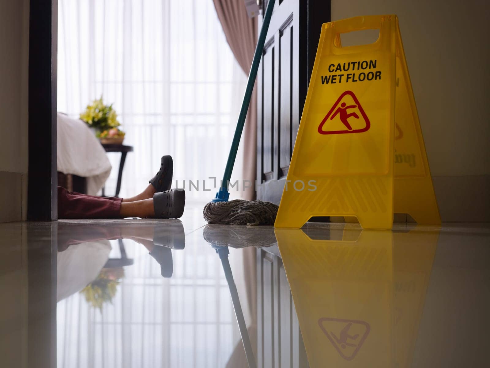 housemaid had accident at work while cleaning floor in hotel room. Side view, low angle