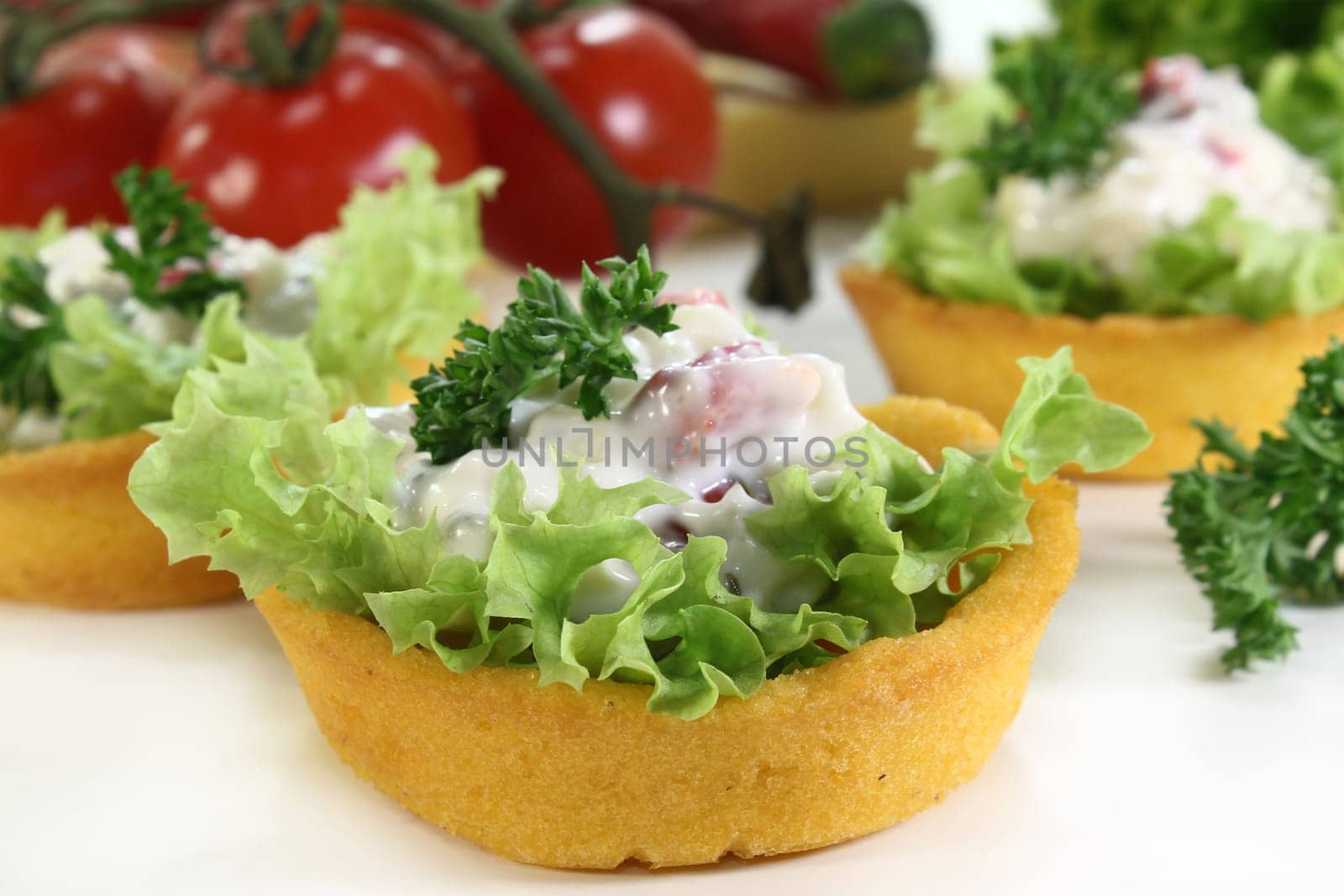 Corn tartlets with cheese salad against white background