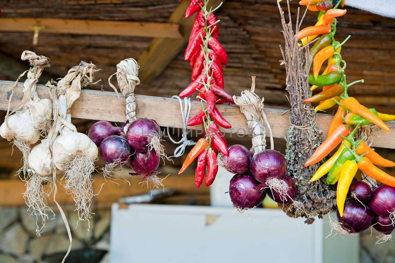 Garlic, onions and coloful peppers a wooden roof