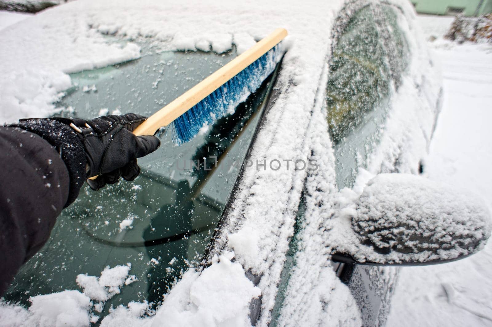 Removing snow from a car window using a brush