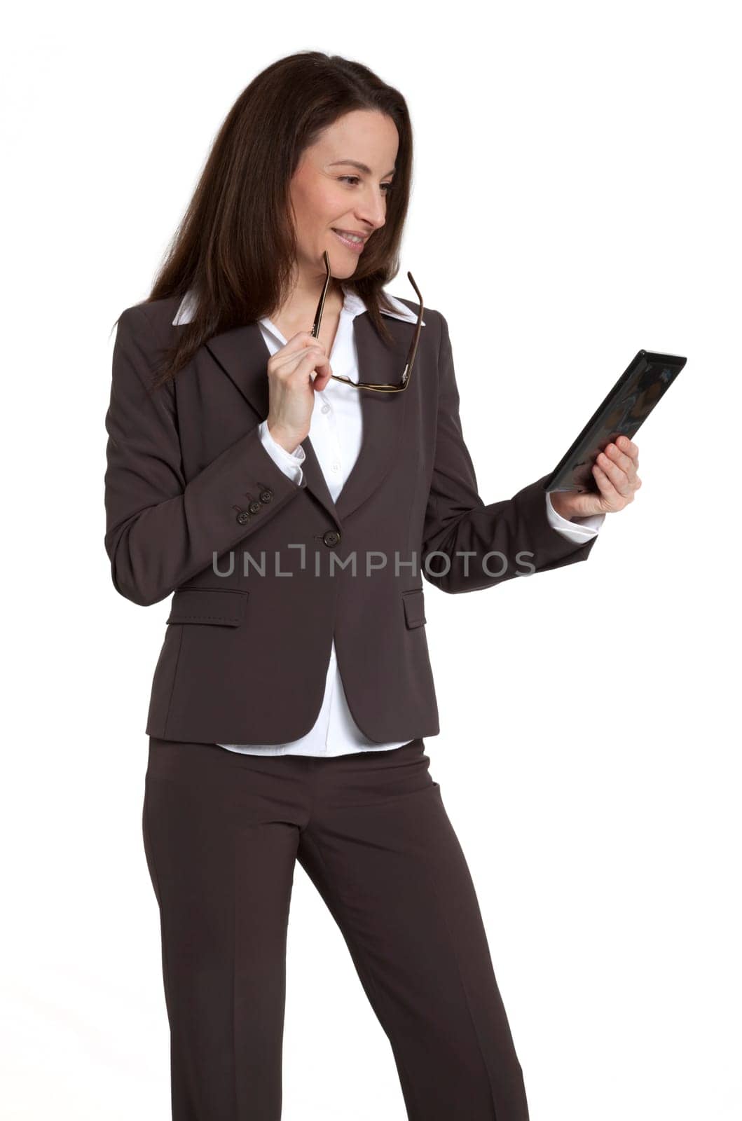Attractive businesswoman holding and looking at tablet device against white background.