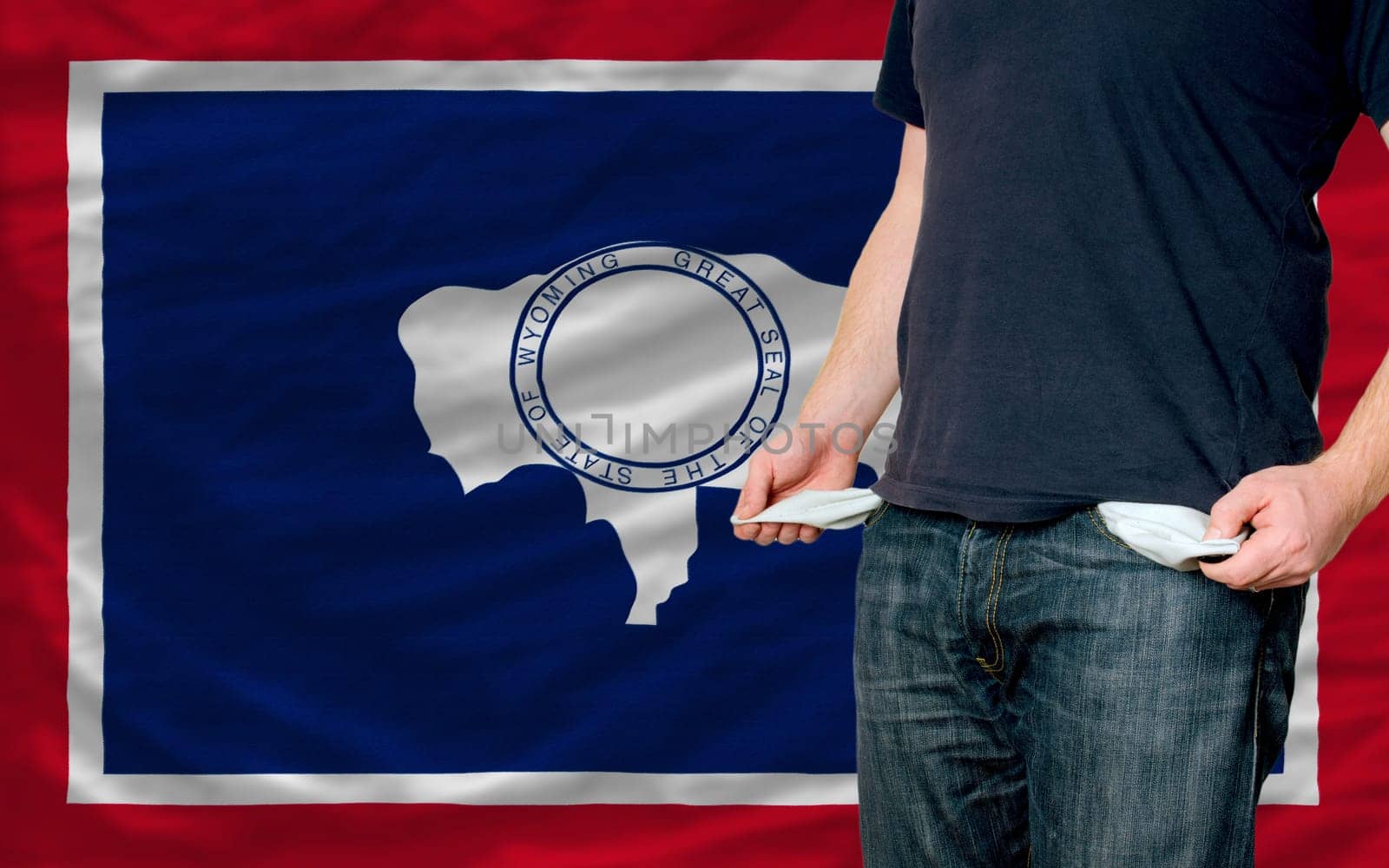 poor man showing empty pockets in front of wyoming flag