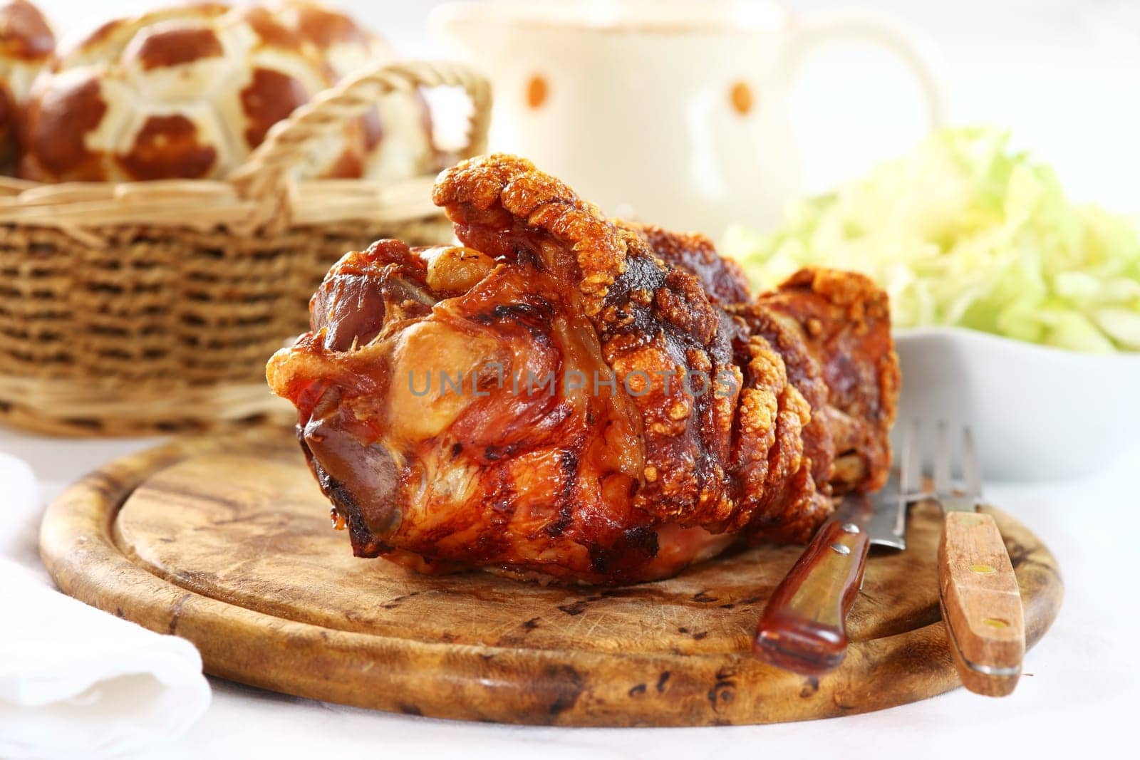 Grilled knuckle of pork with bread rolls and lettuce salad