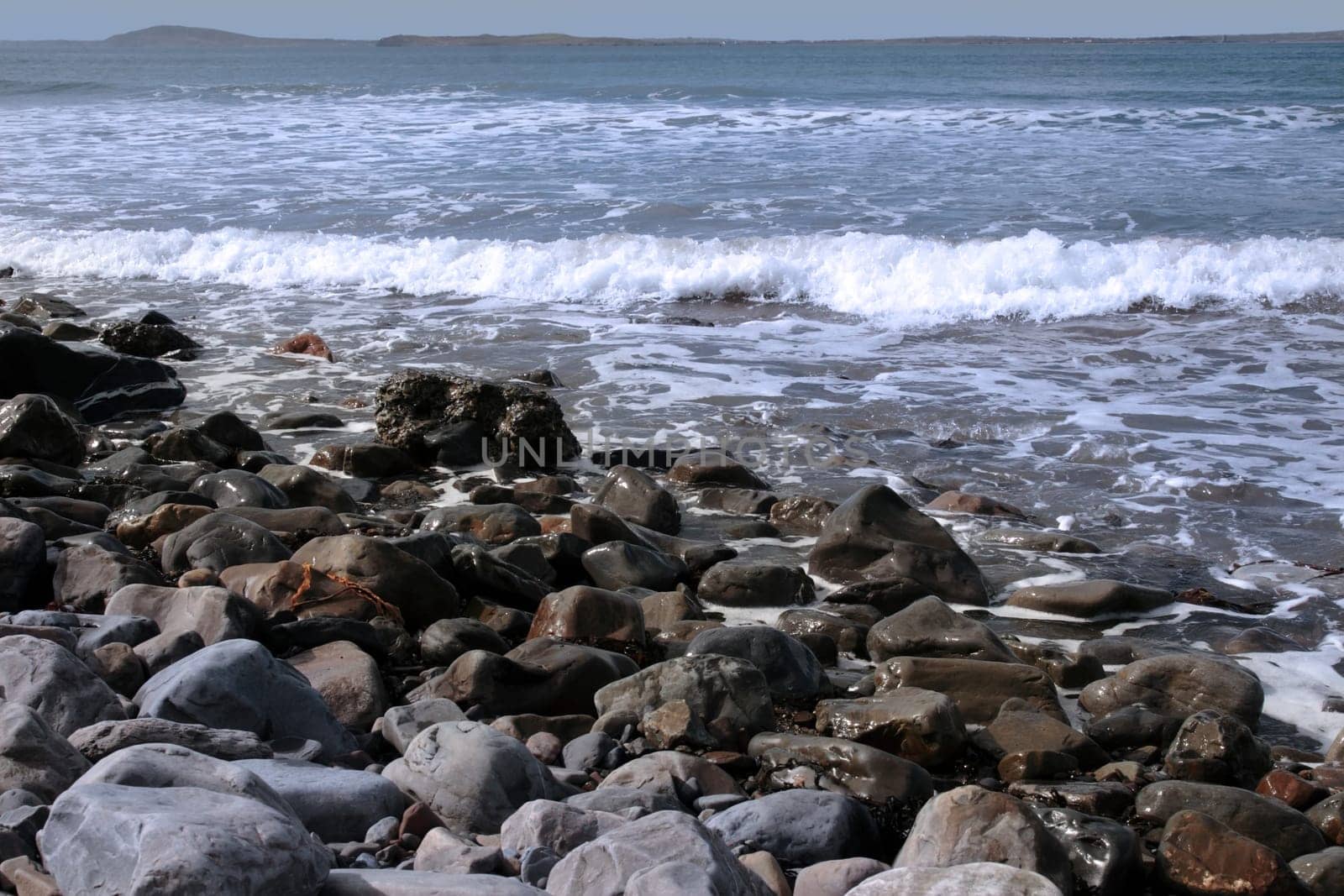 a pebbled beach on a warm day with a calm sea as a background