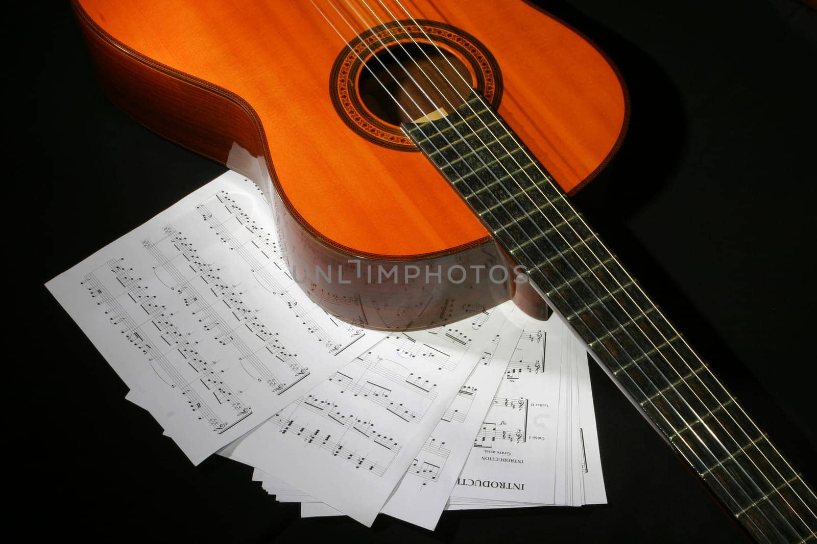 Guitar and music sheet on the black background
