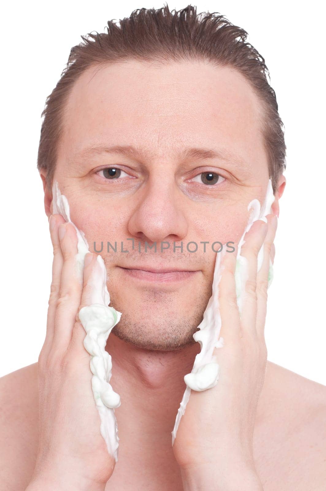 A smiling man smears shaving cream on his facial cheeks