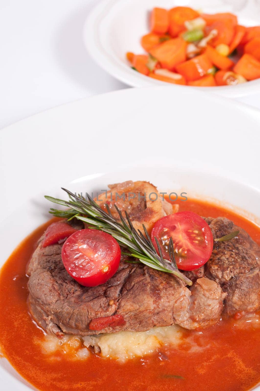 Ossobuco,braised veal shank slices with rosemary and tomatoes and tomato sauce and carrots as a side dish